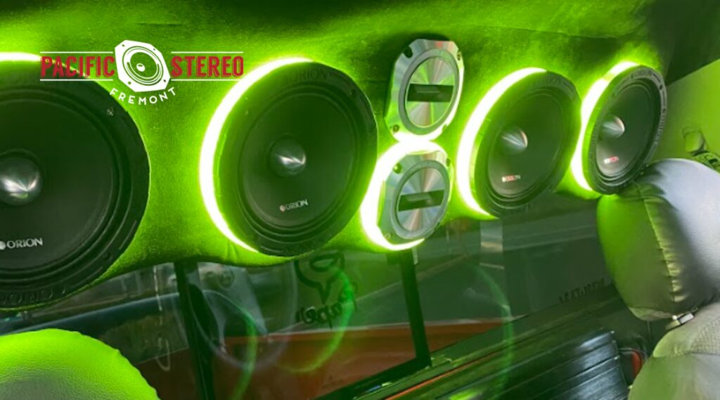 Custom car audio system installation with neon green LED-lit Orion speakers inside a vehicle in Fremont, CA, showcasing high-end audio upgrades.