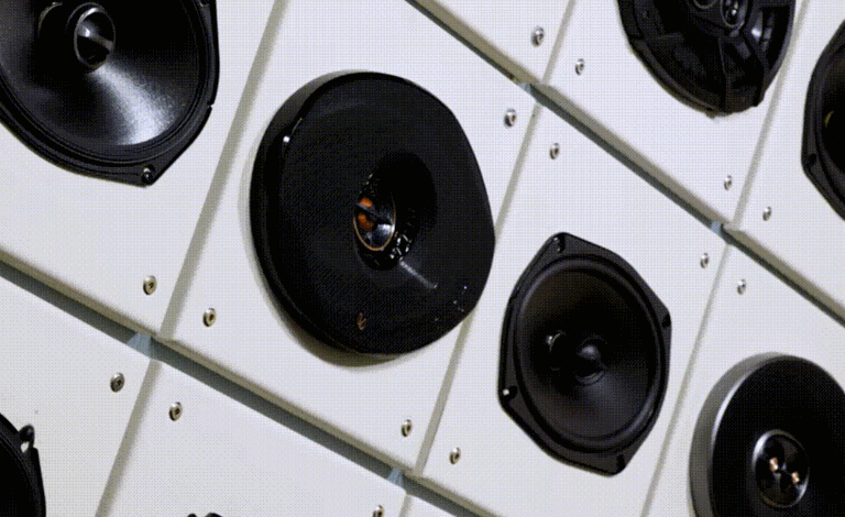 Wall-mounted display of various car audio speakers, showcasing different shapes, sizes, and speaker cone materials.